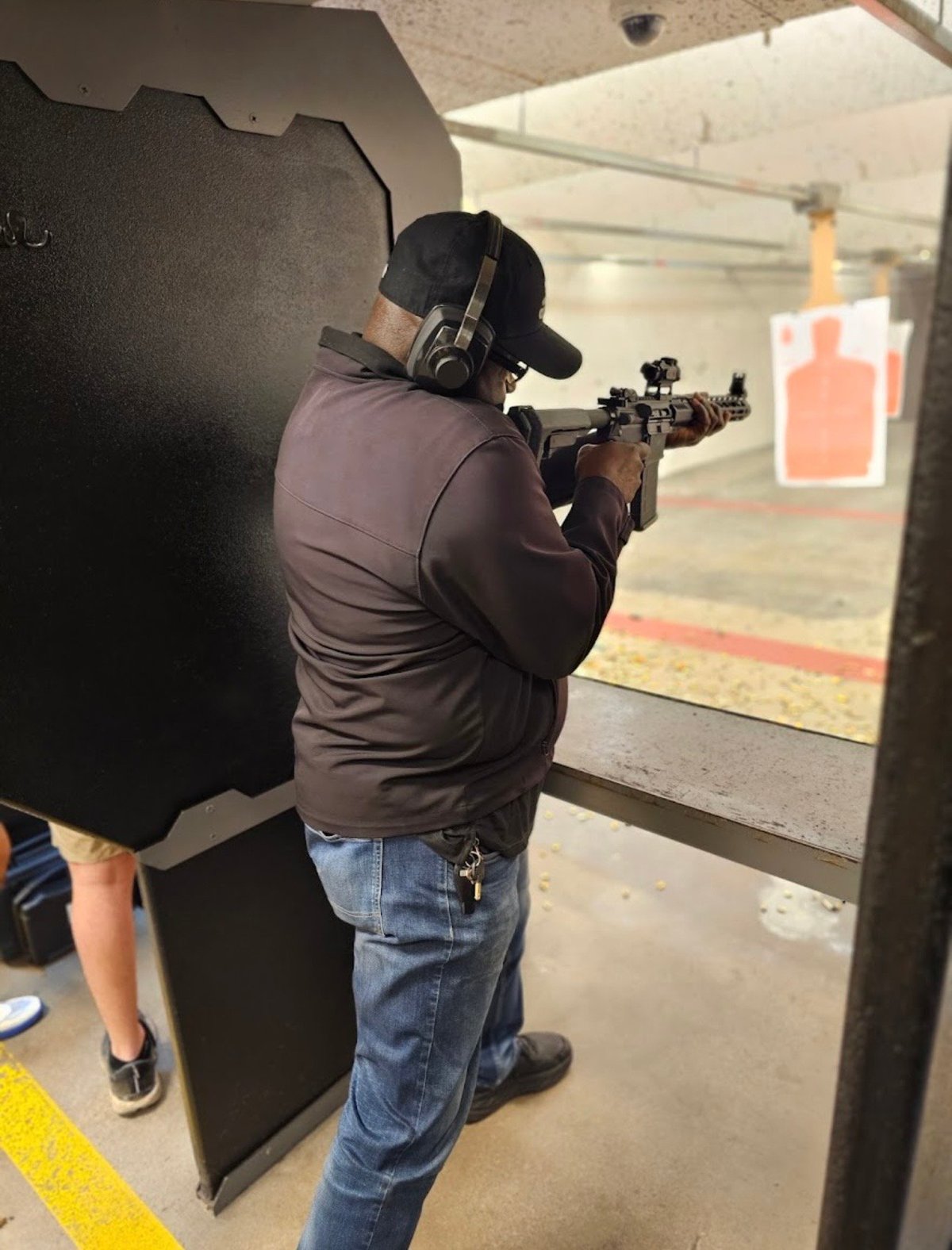 Shooter aiming rifle at indoor shooting range with target downrange
