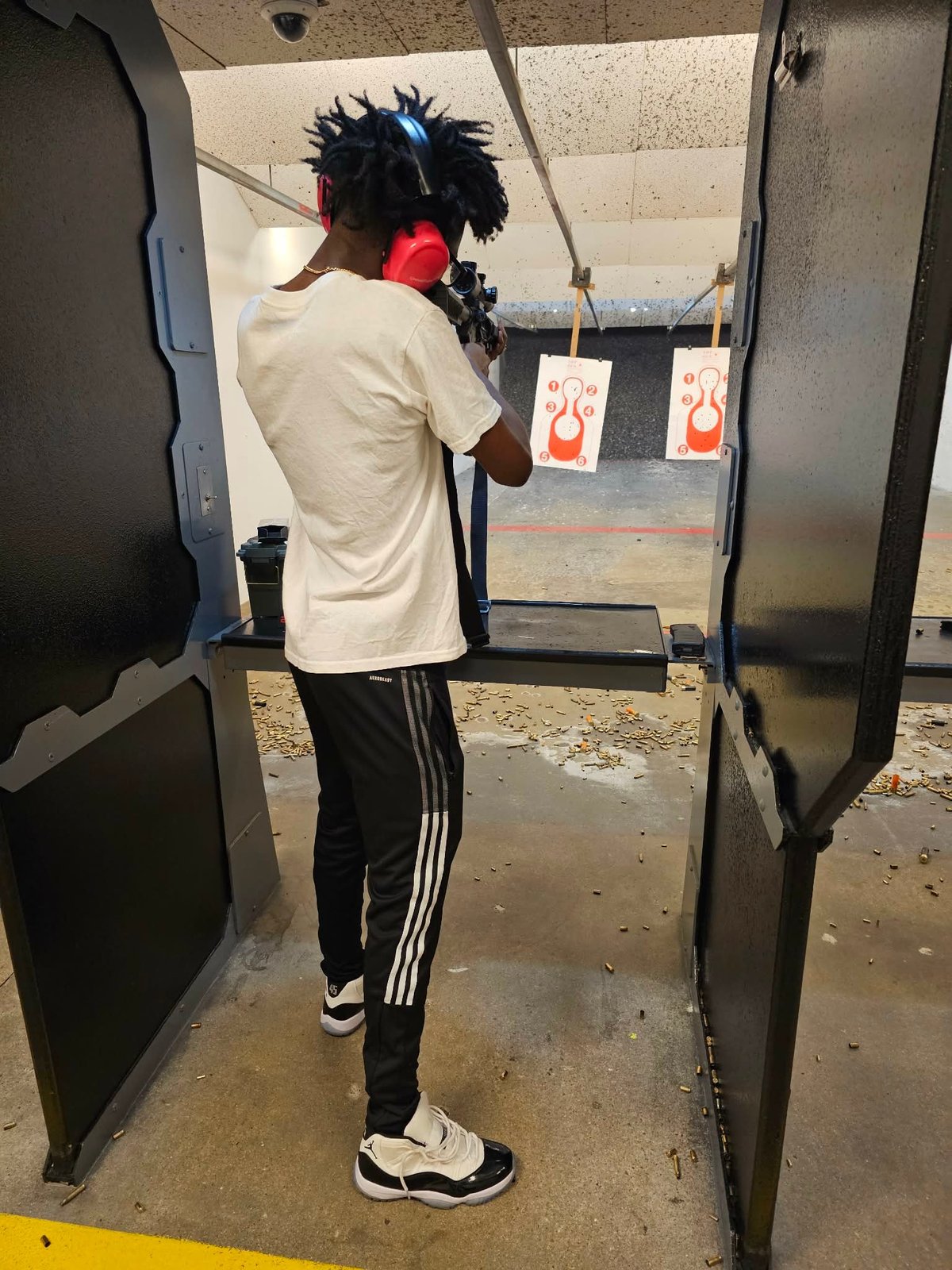 Person aiming a rifle at targets in an indoor shooting range facility